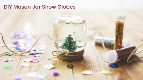 DIY Mason Jar Snow Globe on wood table with glitter